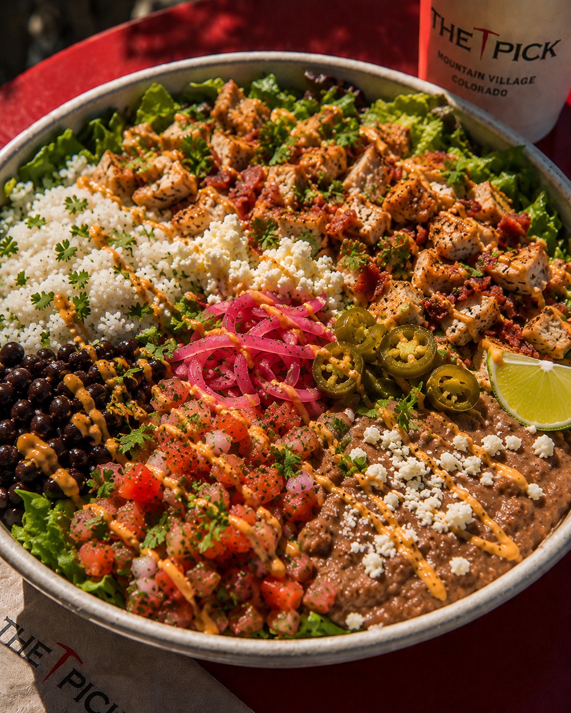 The San Juan bowl from The Pick with chicken, bacon, cotija, black beans, pickled onions, jalapeños, and refried beans